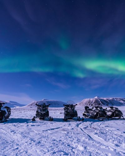 The polar arctic Northern lights aurora borealis sky star in Norway Svalbard in Longyearbyen city snowmobile the moon mountains